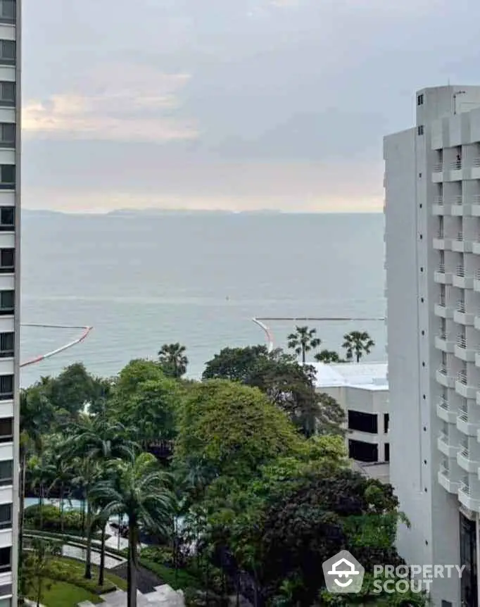 Stunning ocean view from high-rise apartment with lush greenery and palm trees.