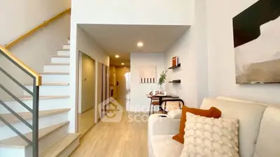Modern living room with staircase and stylish decor in a bright, open space.
