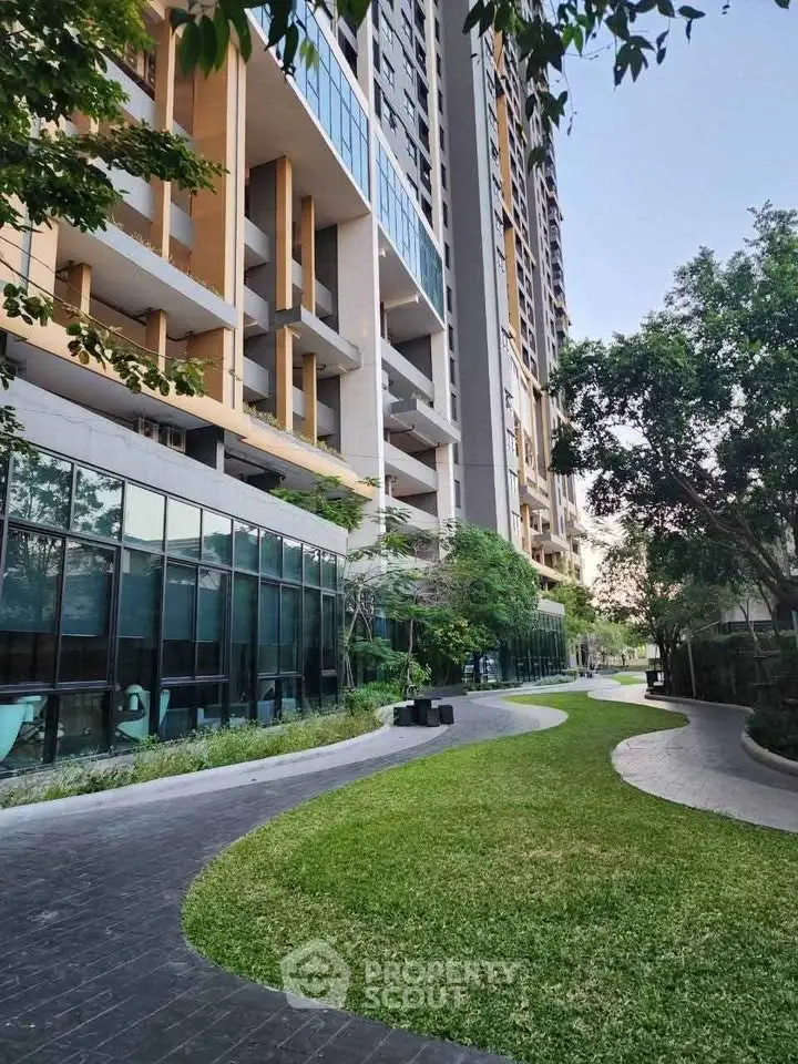 Modern high-rise building with lush landscaped garden and glass facade