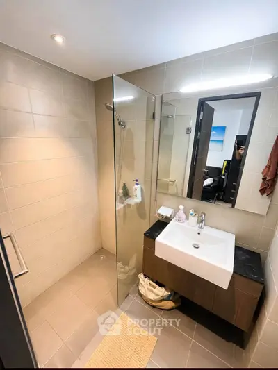 Modern bathroom with glass shower and sleek vanity in contemporary apartment.