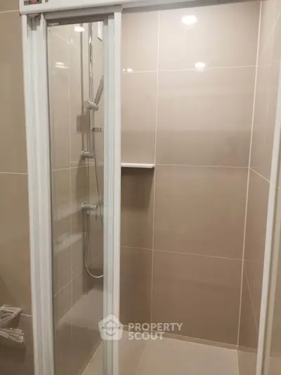 Modern bathroom with sleek shower enclosure and beige tiles.