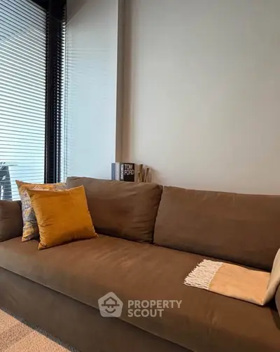 Stylish living room with modern brown sofa and decorative pillows, perfect for cozy relaxation.