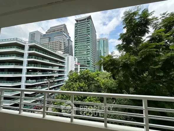Stunning urban view from a balcony overlooking modern skyscrapers and lush greenery.