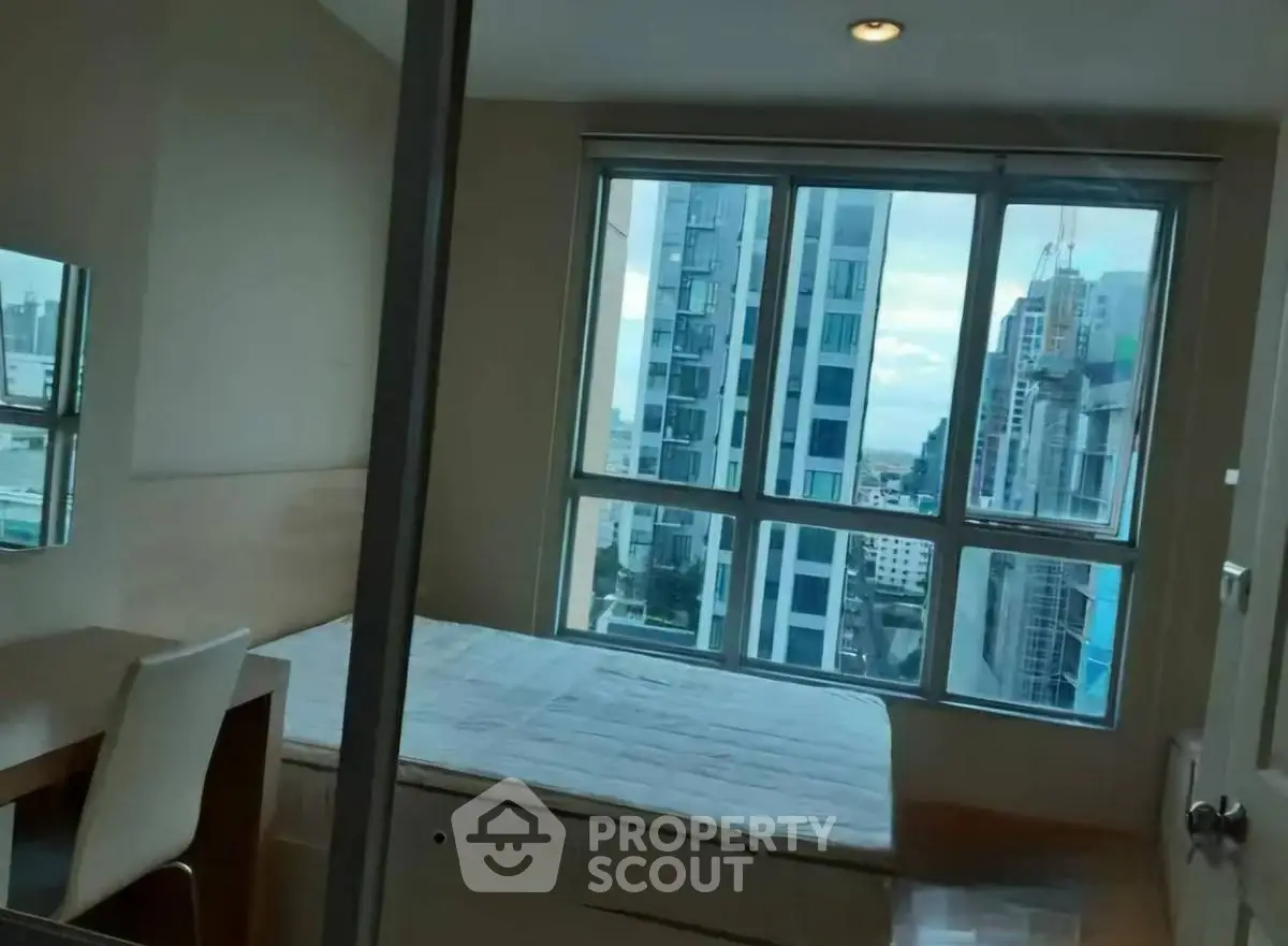 Modern bedroom with city view and large windows in high-rise apartment