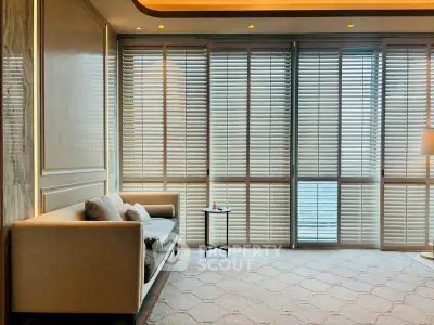 Luxurious living room with elegant sofa and floor-to-ceiling windows with blinds.
