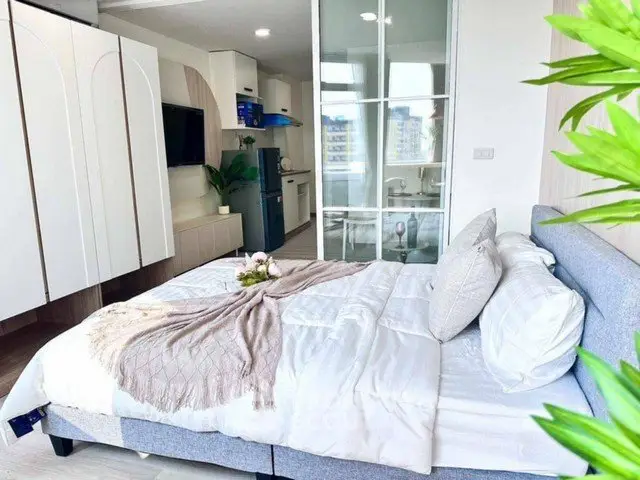 Modern bedroom with stylish decor and open kitchen layout in a bright apartment.