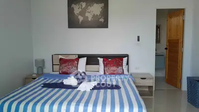 Cozy bedroom with stylish decor and world map artwork, featuring a neatly made bed with swan towel arrangement.