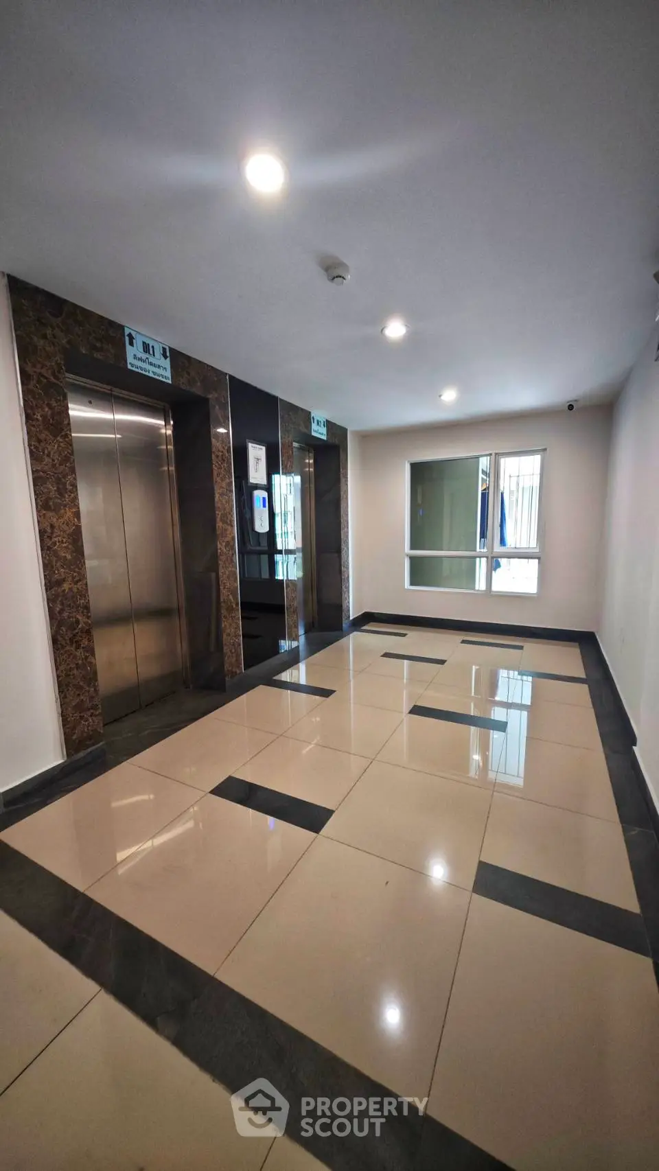 Modern building lobby with sleek elevator and polished tile flooring
