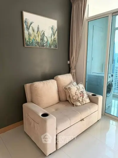 Cozy living room with plush sofa and balcony view, perfect for relaxation and modern living.