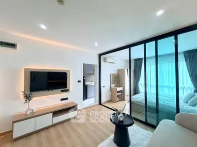 Modern living room with glass partition leading to a cozy bedroom, featuring sleek furniture and ambient lighting.