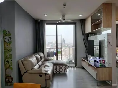 Modern living room with large window and city view, featuring a comfortable sofa and sleek entertainment unit.