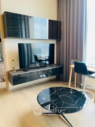 Modern living room with sleek black furniture and large TV, featuring a stylish marble coffee table.