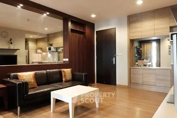 Modern living room with sleek design and open kitchen layout, featuring wooden flooring and contemporary furniture.