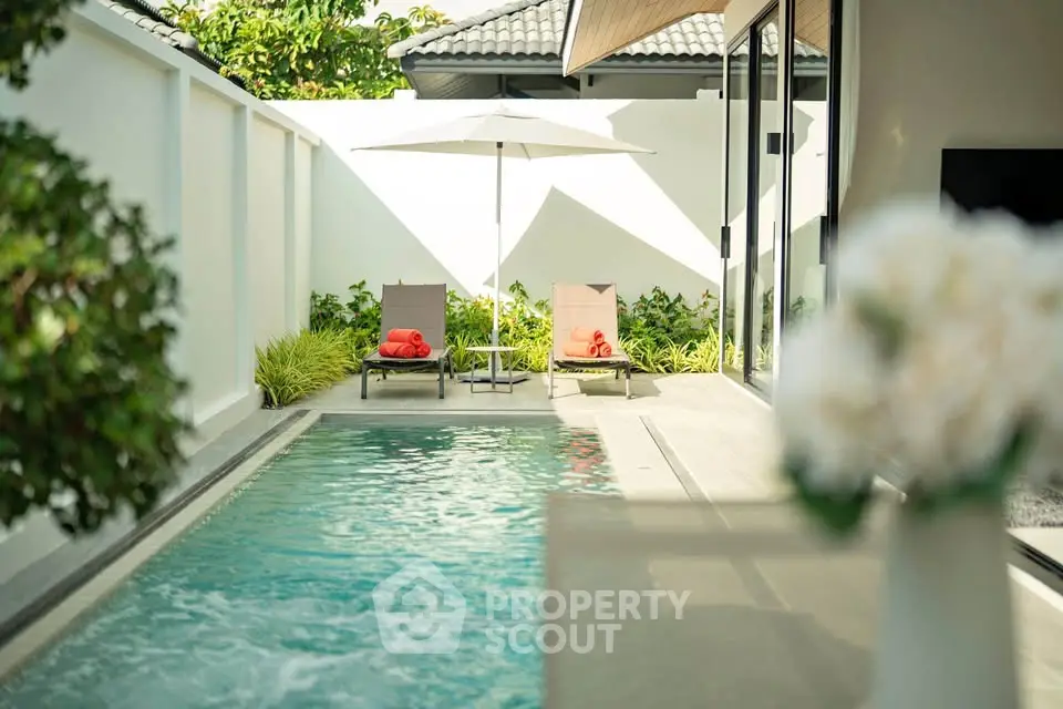 Luxurious private pool area with sun loungers and umbrella, perfect for relaxation and leisure.