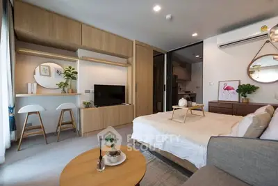 Modern studio apartment with stylish decor and open layout, featuring a cozy bed and functional workspace.