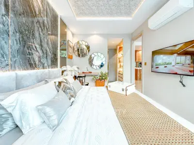 Luxurious bedroom with modern decor, featuring a stylish bed, wall-mounted TV, and elegant lighting.