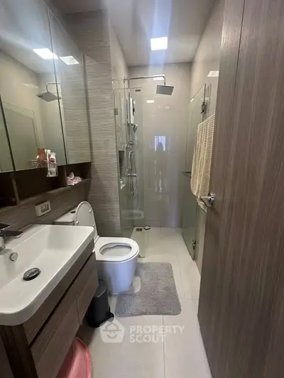 Modern bathroom with glass shower, sleek vanity, and contemporary fixtures in a stylish apartment.