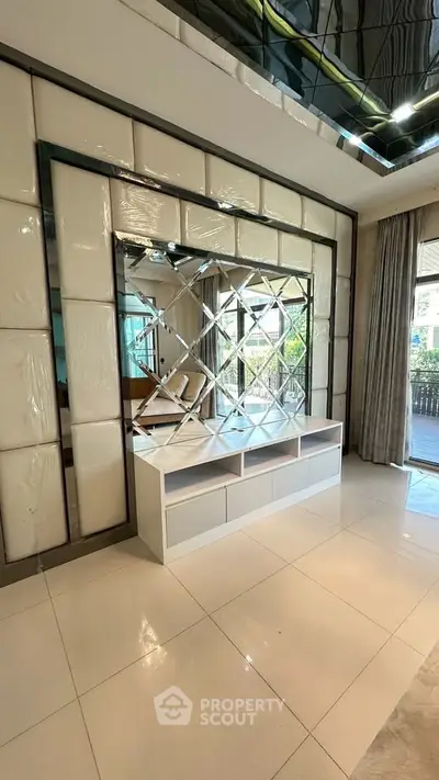 Luxurious modern living room with elegant mirrored wall and sleek white storage unit.