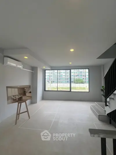 Spacious modern living room with large windows and staircase, ideal for urban living.