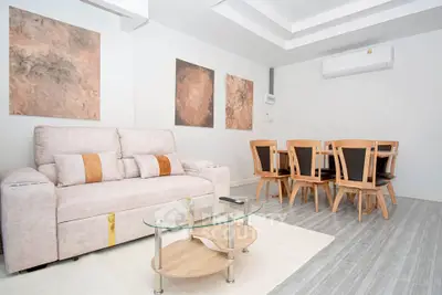 Modern living room with elegant sofa and dining set, featuring stylish wall art and sleek flooring.