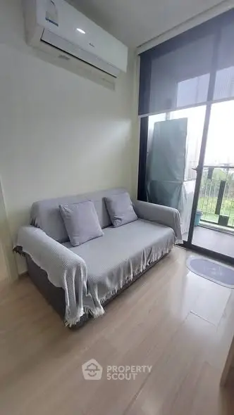 Cozy living room with modern sofa and air conditioning, featuring a balcony view.