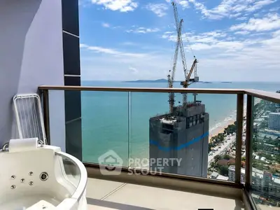 Luxurious balcony with jacuzzi offering stunning ocean and city views in high-rise building.