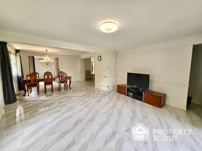 Expansive and elegantly tiled living room with abundant natural light, featuring a classic dining set and a cozy entertainment area.