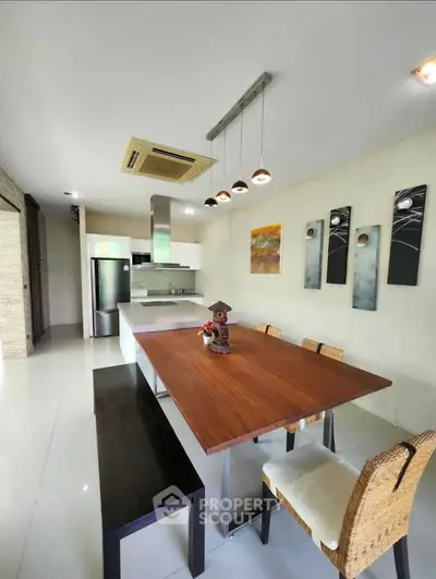 Modern kitchen with sleek design, featuring a wooden dining table and contemporary lighting.