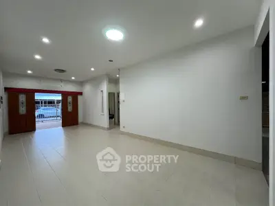 Spacious empty living room with tiled flooring and bright lighting, ideal for customization.