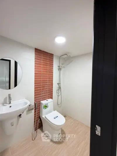 Modern bathroom with sleek fixtures and stylish red brick accent wall.