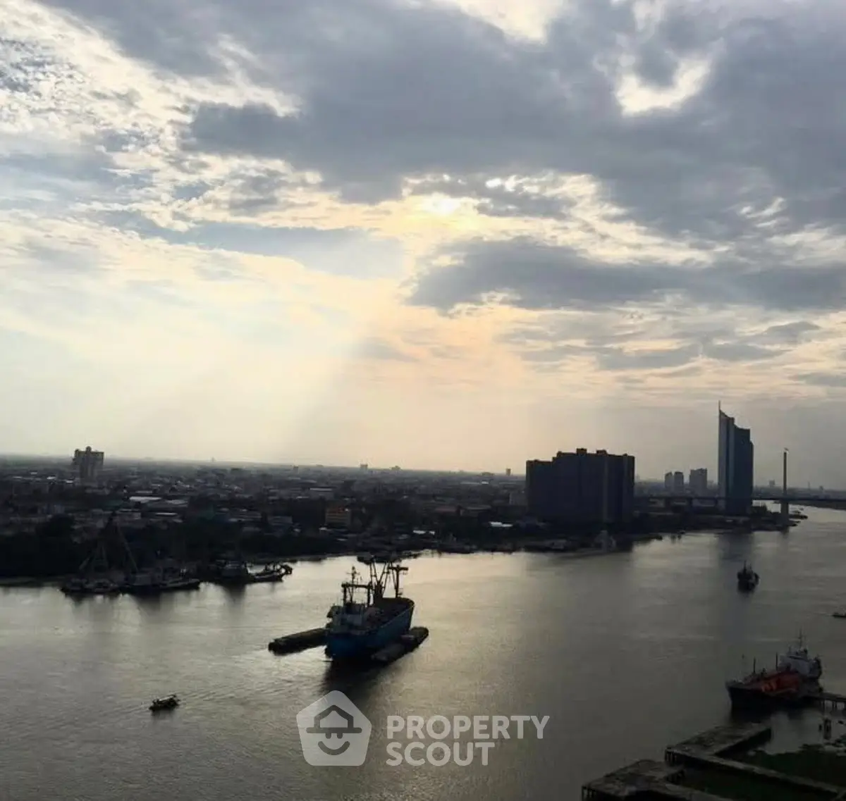 Stunning river view with city skyline and dramatic clouds at sunset, perfect for urban living.