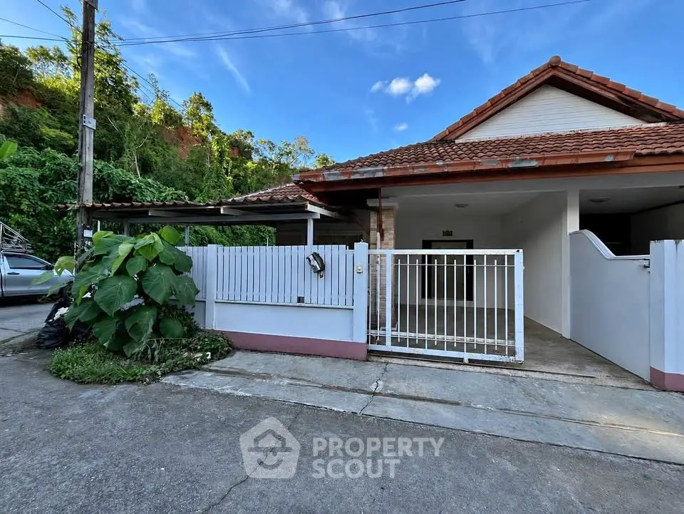 Charming single-story house with tiled roof and gated driveway in a serene neighborhood.