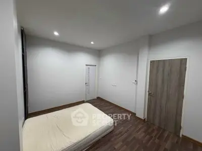 Minimalist bedroom with wooden flooring and recessed lighting