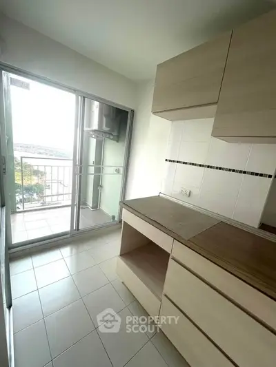 Bright kitchen with balcony access and modern cabinetry in a high-rise apartment.