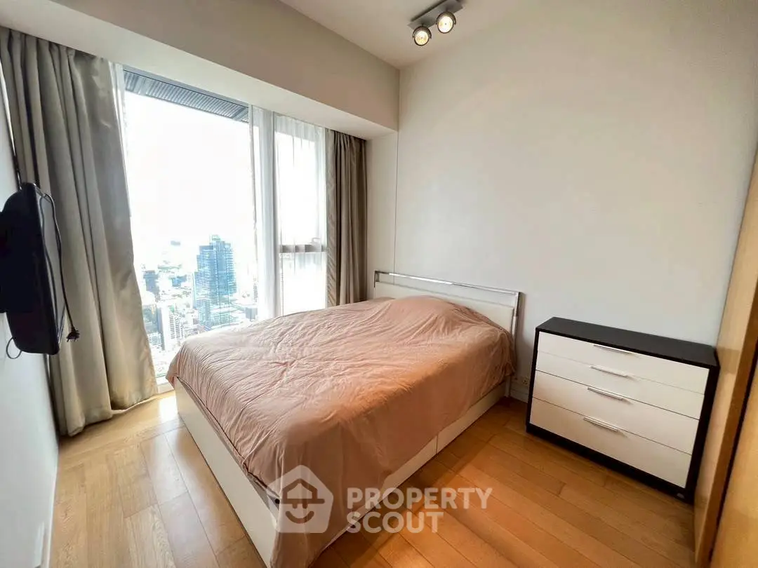 Modern bedroom with city view, wooden flooring, and sleek furniture in a high-rise apartment.