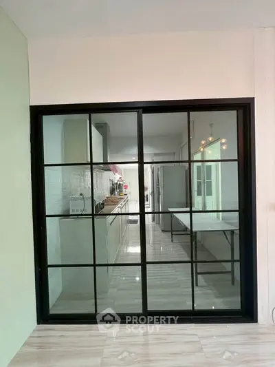 Modern kitchen with sleek black-framed glass doors and contemporary design.