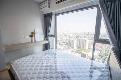 Modern bedroom with panoramic city view and large windows in high-rise apartment.