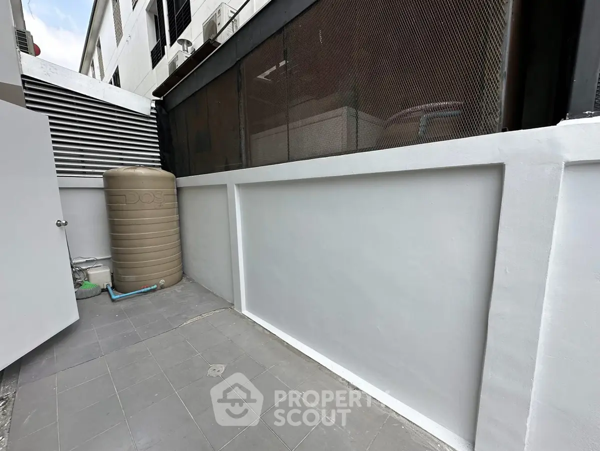 Modern outdoor area with sleek design and neutral tones, featuring a water tank and tiled flooring.