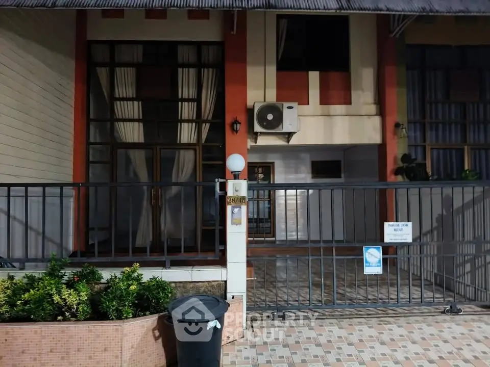 Charming residential entrance with gated patio and lush greenery, perfect for a cozy home.