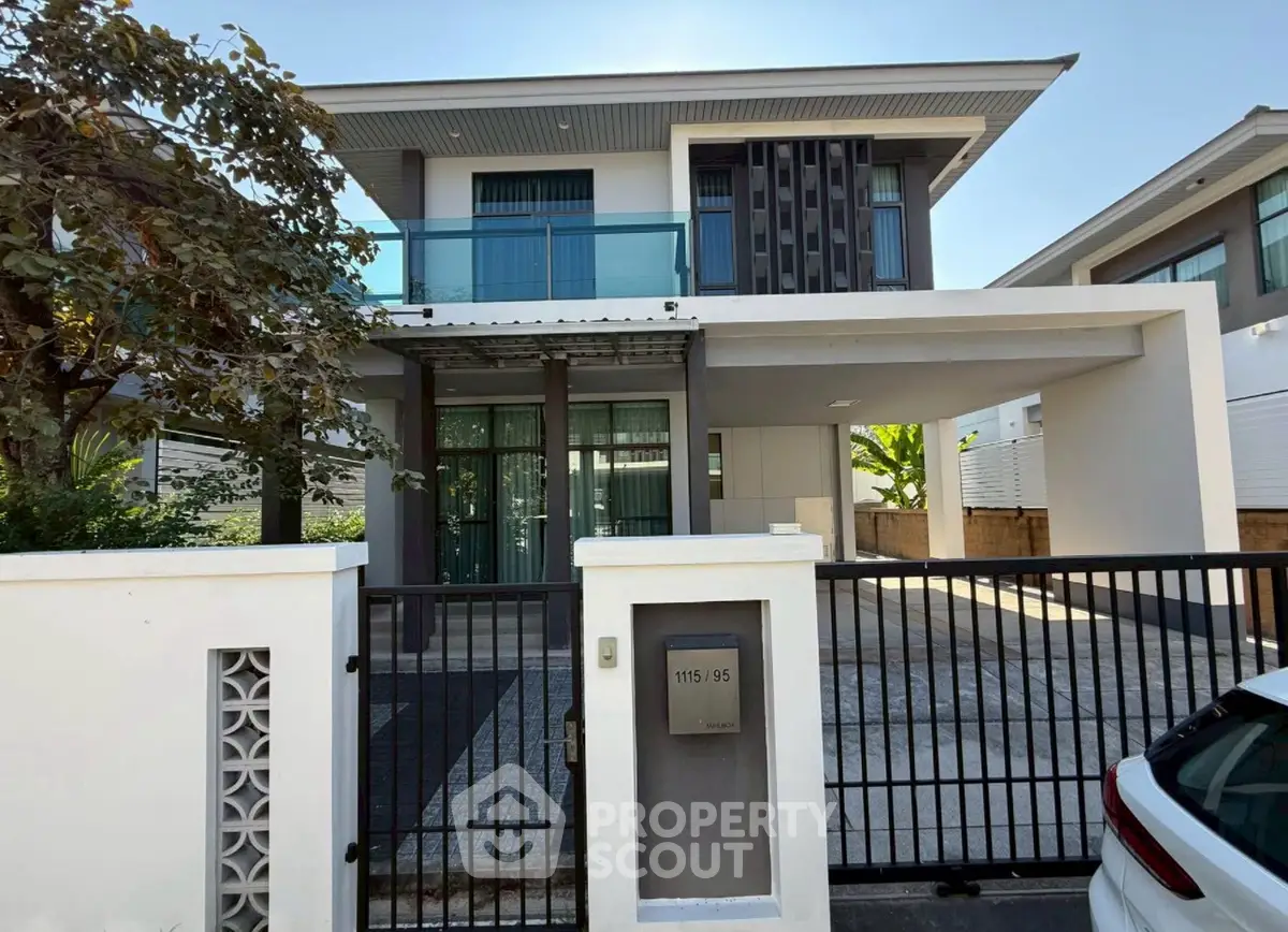 Modern two-story house with sleek design and gated entrance in a serene neighborhood.