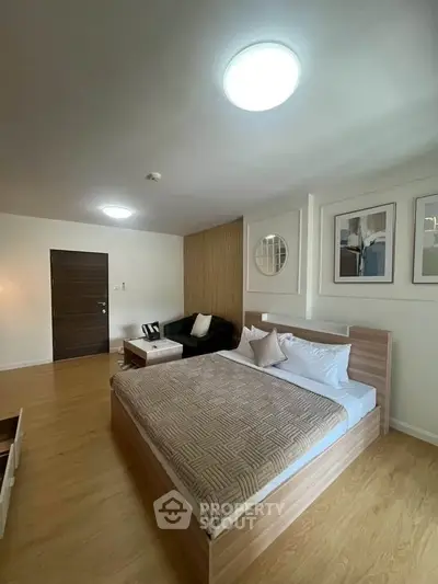 Spacious modern bedroom with stylish decor and cozy ambiance, featuring wooden flooring and contemporary furniture.