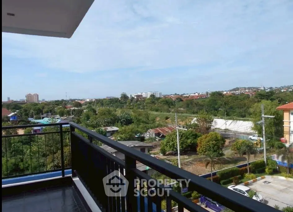 Spacious balcony with scenic view of lush greenery and distant cityscape.