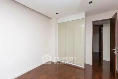 Spacious bedroom with sleek built-in wardrobe and polished wooden floors.