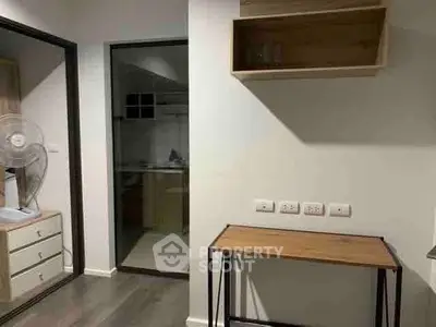 Modern interior with minimalist furniture and open layout, featuring a small desk and shelving unit.