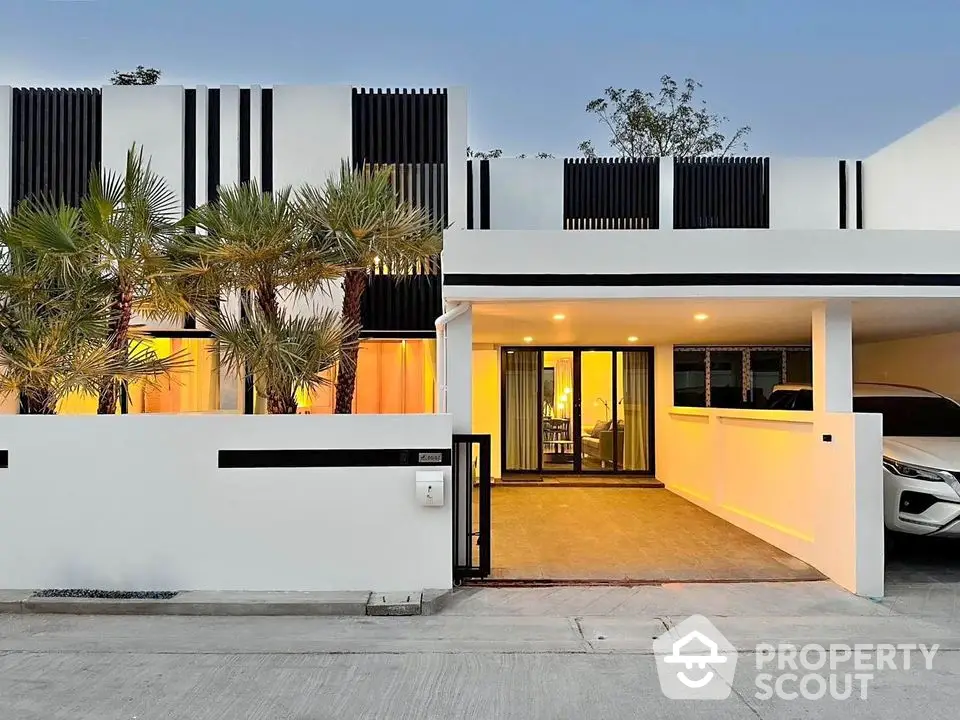 Modern minimalist house exterior with carport and palm trees at sunset