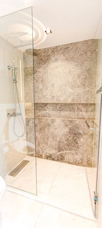 Luxurious modern bathroom with glass shower enclosure and elegant stone wall design.