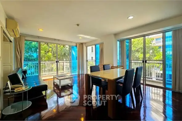 Spacious living room with large windows and elegant dining area, featuring abundant natural light and modern furnishings.