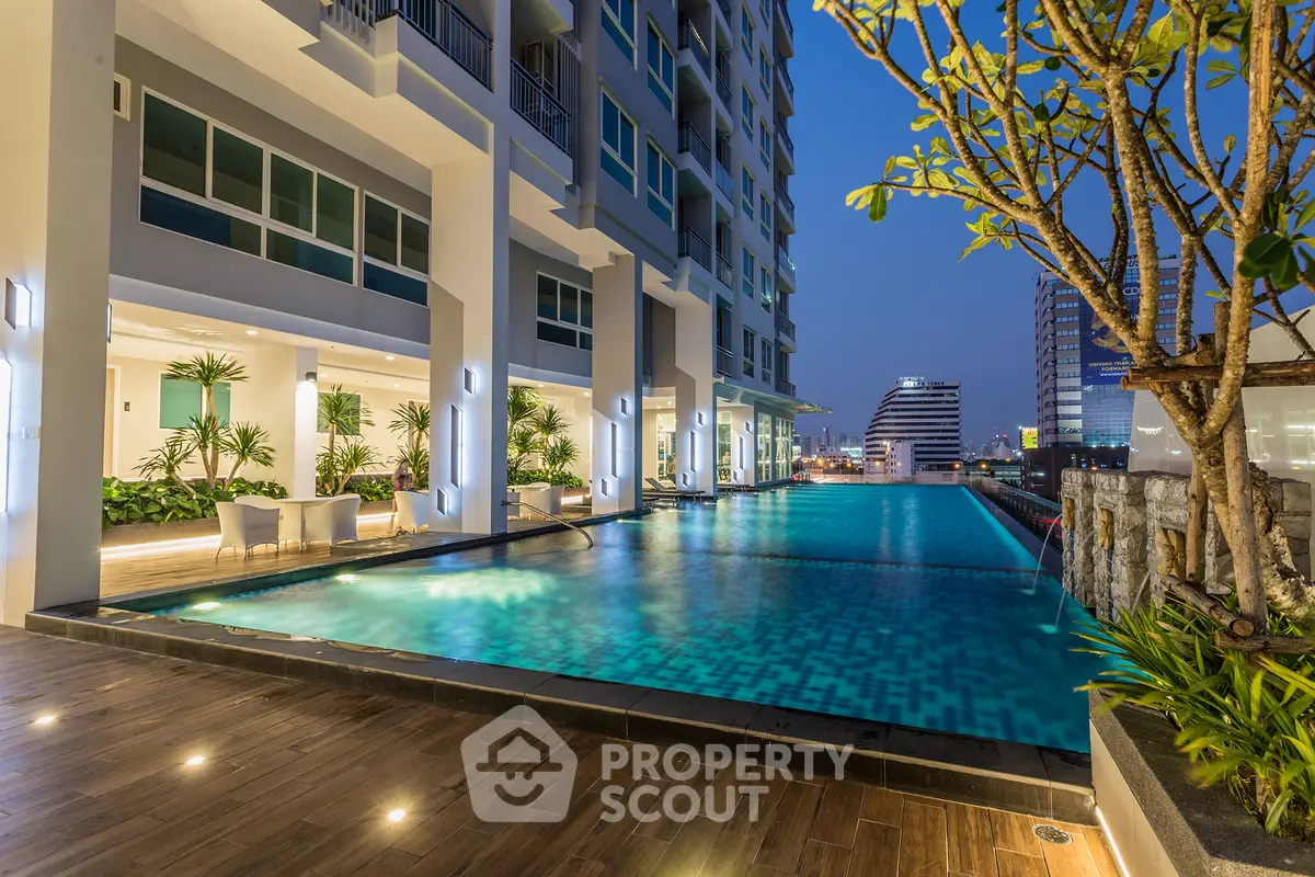 Luxurious high-rise building with stunning rooftop pool and city views at dusk.