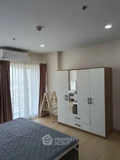 Spacious bedroom with modern wardrobe and natural light in a stylish apartment.