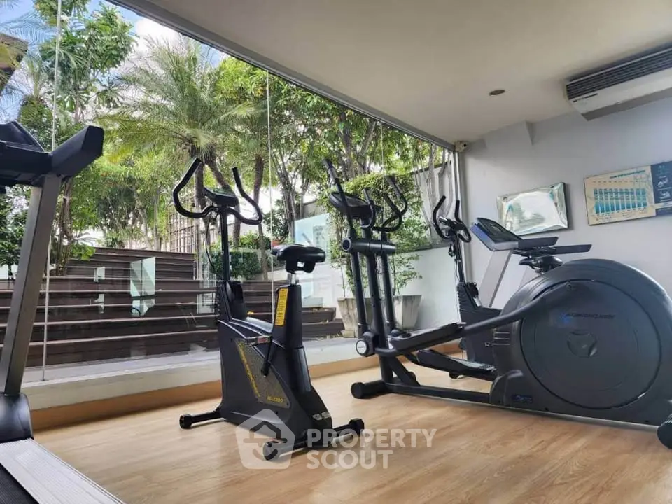Modern gym with exercise bikes and treadmill in a bright, glass-walled space.